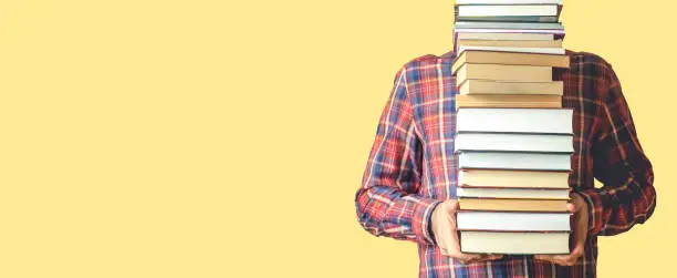 Student with books on a blank colored banner background. Education, reading and study background concept.