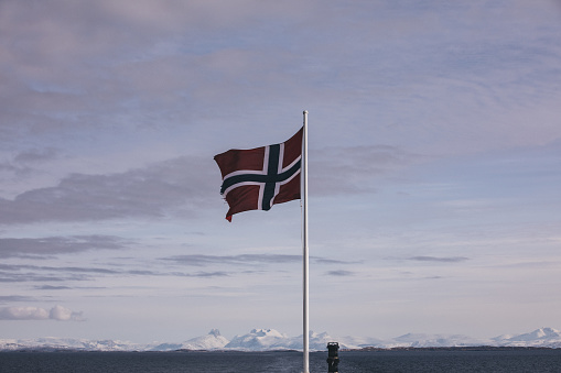 Norway flag on ship against snowy mountains landscape