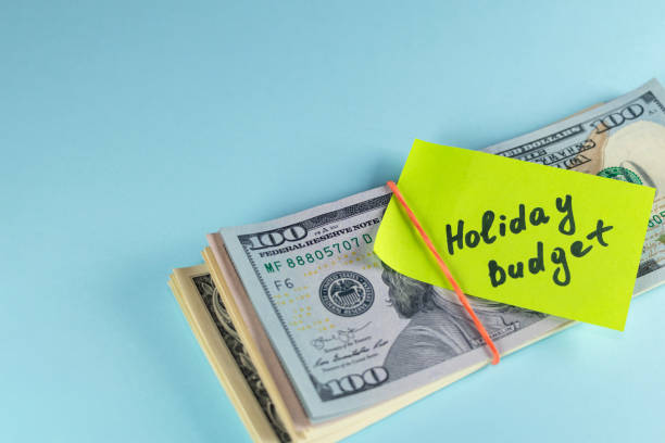 istock Text written note Holiday budget, dollars cash money in rubber band with note, on copy space background - concept of financial planning of set budget for Christmas or holiday 1304920143