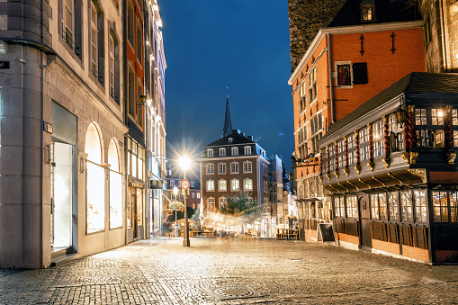 illuminated town square in the historic center of Aachen at blue hour with few people in street restaurant