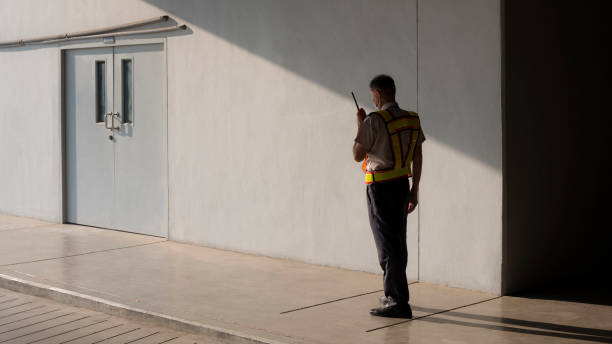 istock Security guard using walkie talkie on sidewalk during survey around the building 1304921851