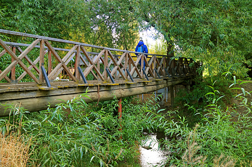 Rear view of a woman with a backpack crossing a bridge.