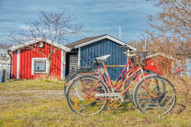 赤い放棄された錆びた自転車は、スカンジナビアのライフスタイルと文化のイラストを提供します。ラックに忘れられた孤独な古い自転車 - klagshamn ストックフォトと画像