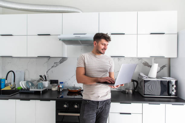 istock Handsome man using a laptop pc in the kitchen. Working from home in quarantine lockdown. Social distancing Self Isolation 1304927149