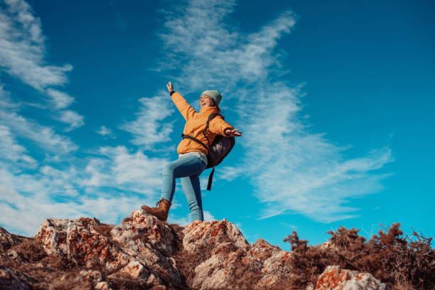 istock Cheering woman backpacker enjoy the view on sunrise mountain top cliff edge 1304928405