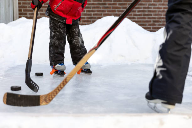 cute boy learning to ice skate and play hockey with his mother in backyard in winter - ice skating ice hockey child family imagens e fotografias de stock
