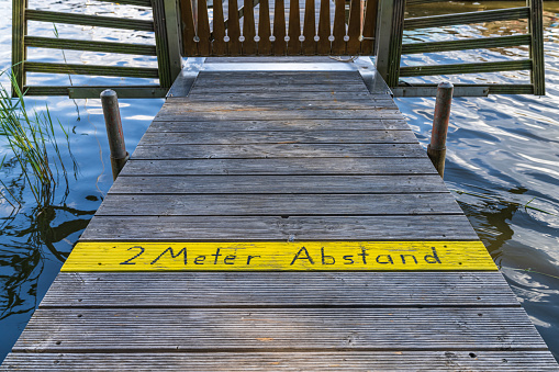 2 Meter Abstand (German for: Keep two meters distance), painted on a jetty in Mardorf, Lower Saxony, Germany