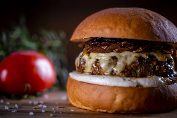 istock Craft beef burger with cheese, caramelized onion and sauce on wooden background 1304932993