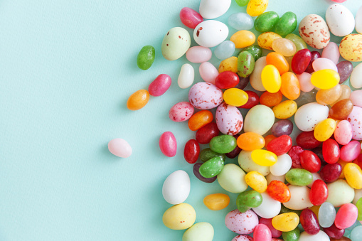 Happy Easter concept. Preparation for holiday. Easter candy chocolate eggs and jellybean sweets isolated on trendy pastel blue background. Simple minimalism flat lay top view copy space