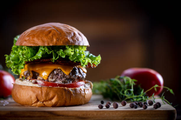 istock Craft beef burger with cheddar, bacon, lettuce and sauce on wooden background 1304933053