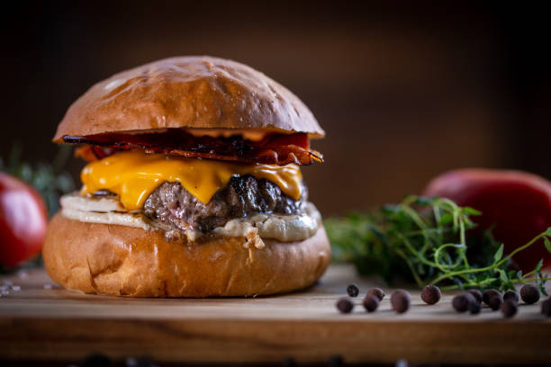 istock Craft beef burger with cheddar, bacon and sauce on wooden background 1304933063