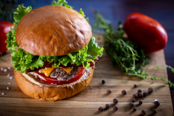 istock Craft beef burger with cheddar, bacon, lettuce and sauce on wooden background 1304933072