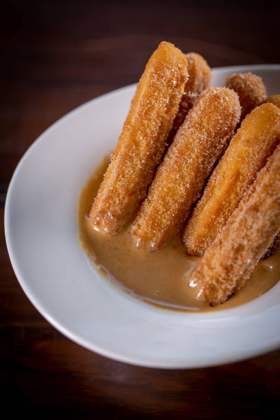 istock Churros sticks with caramel in a wooden background 1304933075