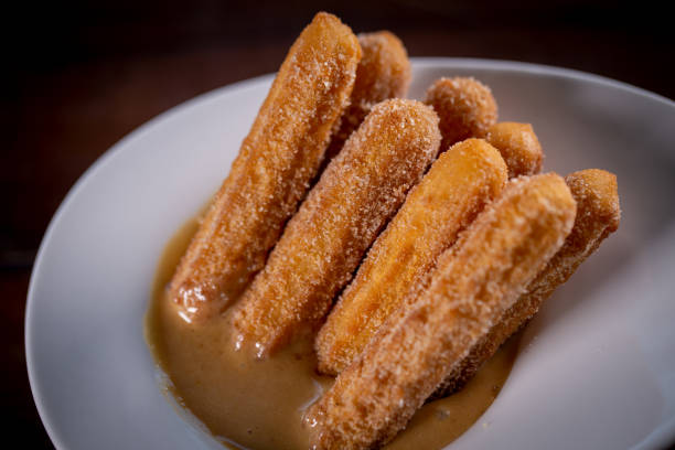 istock Churros sticks with caramel in a wooden background 1304933086