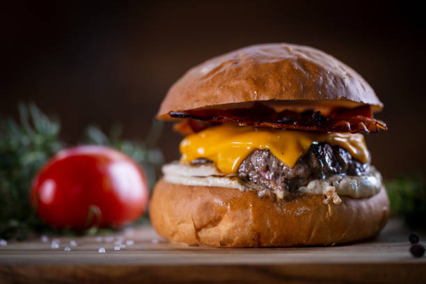 istock Craft beef burger with cheddar, bacon and sauce on wooden background 1304933091