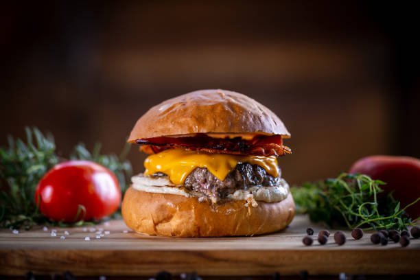 istock Craft beef burger with cheddar, bacon and sauce on wooden background 1304933106