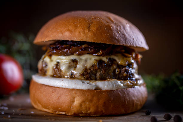 istock Craft beef burger with cheese, caramelized onion and sauce on wooden background 1304933162