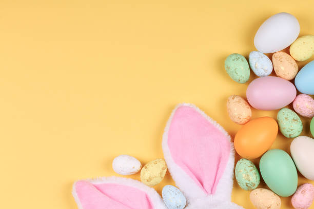 istock Easter yellow background with colorful eggs and bunny ears. 1304934014