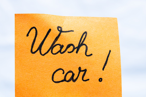 Wash car handwriting text close up isolated on yellow paper with copy space.