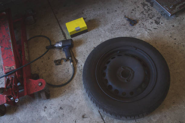 istock Car mechanic tools (tires, scissors, jack, screwdriver) on the ground with copy space. 1304935256