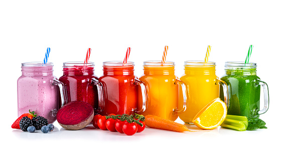 Collection of healthy fresh organic fruits and vegetables smoothies in Mason jars arranged in a row on white background. Fruits and vegetables included in the composition are strawberries, blueberries, beetroot, tomatoes, carrots, oranges, celery, cucumber and spinach. High resolution 42Mp studio digital capture taken with Sony A7rII and Sony FE 90mm f2.8 macro G OSS lens