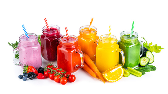 High angle view of a collection of healthy fresh organic fruits and vegetables smoothies in Mason jars arranged in a row on white background. Fruits and vegetables included in the composition are strawberries, blueberries, beetroot, tomatoes, carrots, oranges, celery, cucumber and spinach. High resolution 42Mp studio digital capture taken with Sony A7rII and Sony FE 90mm f2.8 macro G OSS lens