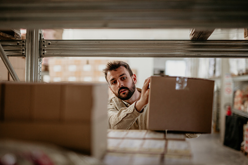 Hardworking warehouse worker relocating boxes in the storage compartment.