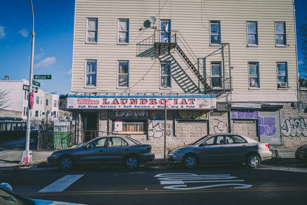 A laundromat window with a neon sign and bags of laundry folded and stacked.