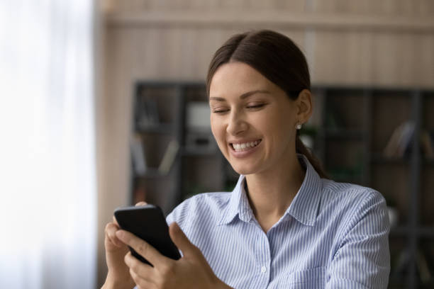 istock Smiling woman use modern smartphone texting online 1304943774