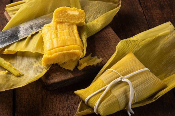 istock Pamonha, Brazilian corn food, called pamonha. On a rustic table with knife and old corn grater, low key portrait, dark abstract background, selective focus. 1304946311