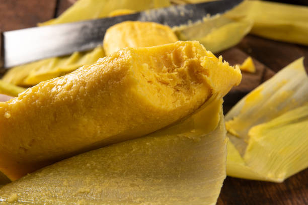 istock Pamonha, Brazilian corn food, called pamonha. On a rustic table with knife and old corn grater, low key portrait, dark abstract background, selective focus. 1304946321