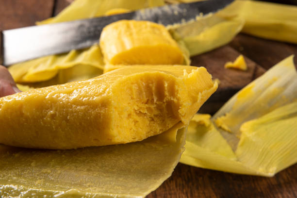 istock Pamonha, Brazilian corn food, called pamonha. On a rustic table with knife and old corn grater, low key portrait, dark abstract background, selective focus. 1304946339