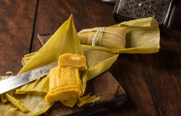 istock Pamonha, Brazilian corn food, called pamonha. On a rustic table with knife and old corn grater, low key portrait, dark abstract background, selective focus. 1304946342