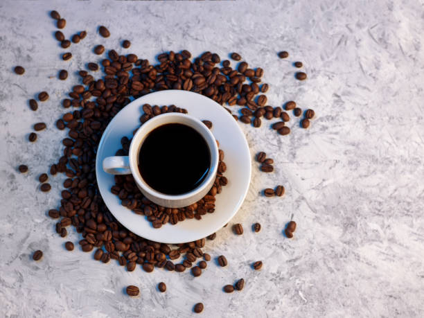 istock Top view of a white espresso cup on a white concrete background, roasted coffee beans, copy space 1304948472