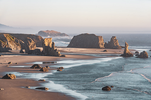 This is a high angle view of the coastal landscape with rock formations on the shore of the Pacific Ocean at Bandon Beach, Oregon at dusk in autumn.