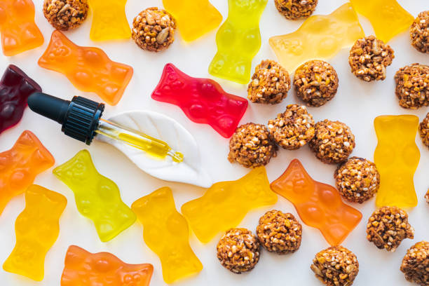 Gummy bears, cbd cookies and thd oil dropper in white backdrop. THD or cannabis sweets in form of gelatine gummi bears and essential oil pipette background: calming edible food supplements cannabis gummy bears stock pictures, royalty-free photos & images