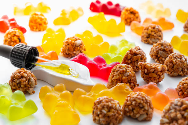 Gummy bears, cbd cookies and thd oil dropper in white backdrop. THD or cannabis sweets in form of gelatine gummi bears and essential oil pipette background: calming edible food supplements cannabis gummy bears stock pictures, royalty-free photos & images