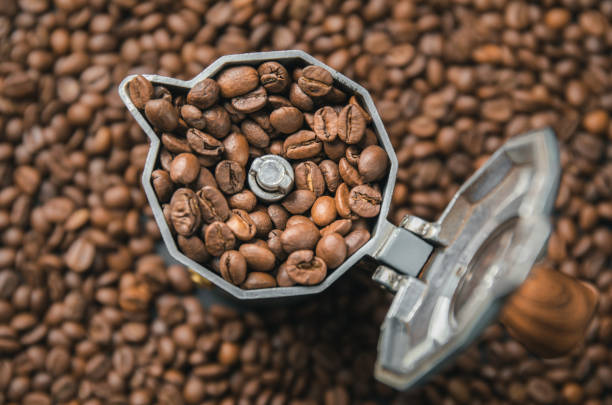istock Top view on mocha pot full with coffee beans. Coffee background concept. 1304954200