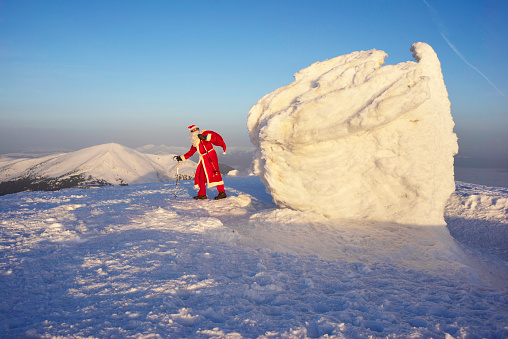 self-portrait: Santa Claus for New Year in a red suit with a bag of gifts at sunrise on the Montenegrin ridge at the top of Hoverla - the highest peak of Ukraine, 2061 meters