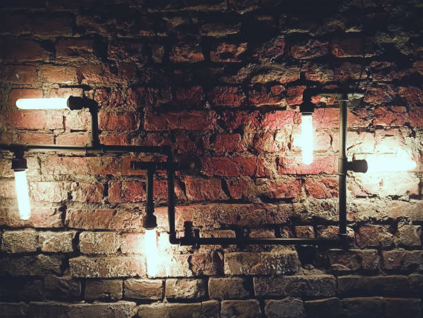 istock Interior design of vintage wall. Rustic design, brick wall with light bulbs and pipes, low lit bar interior 1304955847