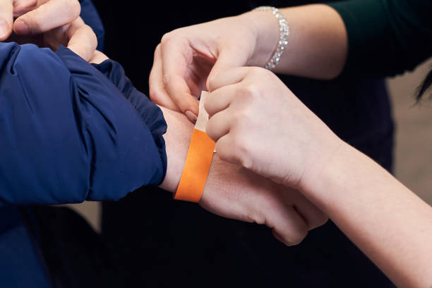 Woman putting a paper bracelet ticket on mans hand stock photo