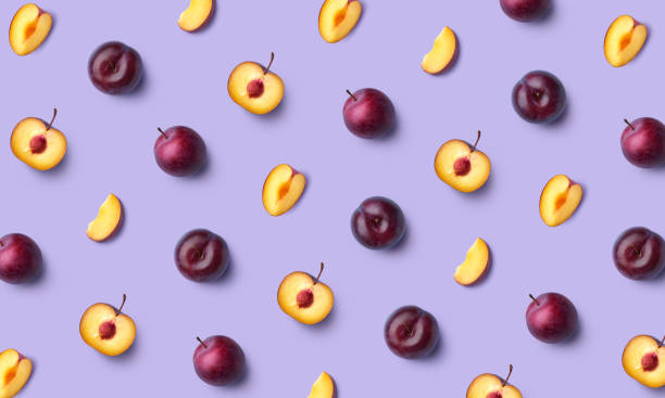 Colorful fruit pattern of fresh whole and sliced plum on purple background Colorful fruit pattern of fresh whole and sliced plum on purple background, flat lay, top view plum stock pictures, royalty-free photos & images