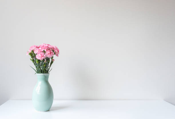 istock Pink carnations in green vase on white table 1304960212