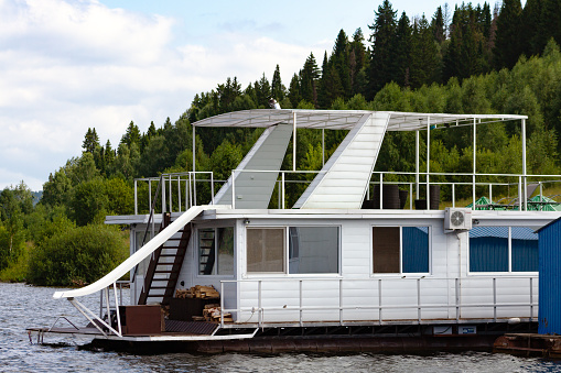 Pavlovsk Reservoir, Russia - August 10, 2018: white houseboat parked on the shore of the reservoir