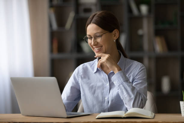 istock Smiling woman work on laptop at home online 1304963593