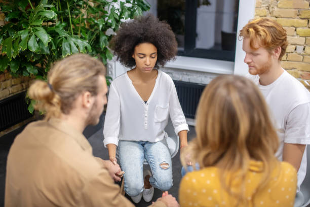 istock Young people sitting in a circle and holding hands 1304964636