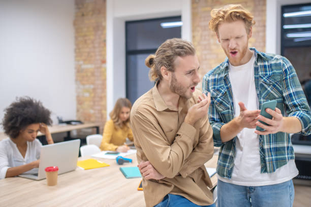 istock Two male colleagues discussing something while looking at the phone abd looking enjoyed 1304964670