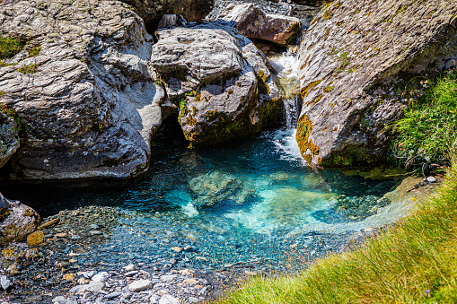 Beautiful turquoise blue water, very clean, surrounded by rocks and grass