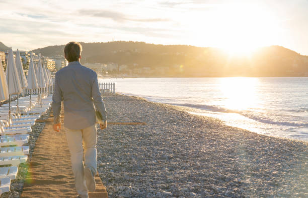 Man walks down empty beach and beach at sunrise