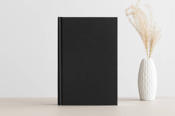 istock Black book mockup with a dried grass decoration on a beige table. 1304972320